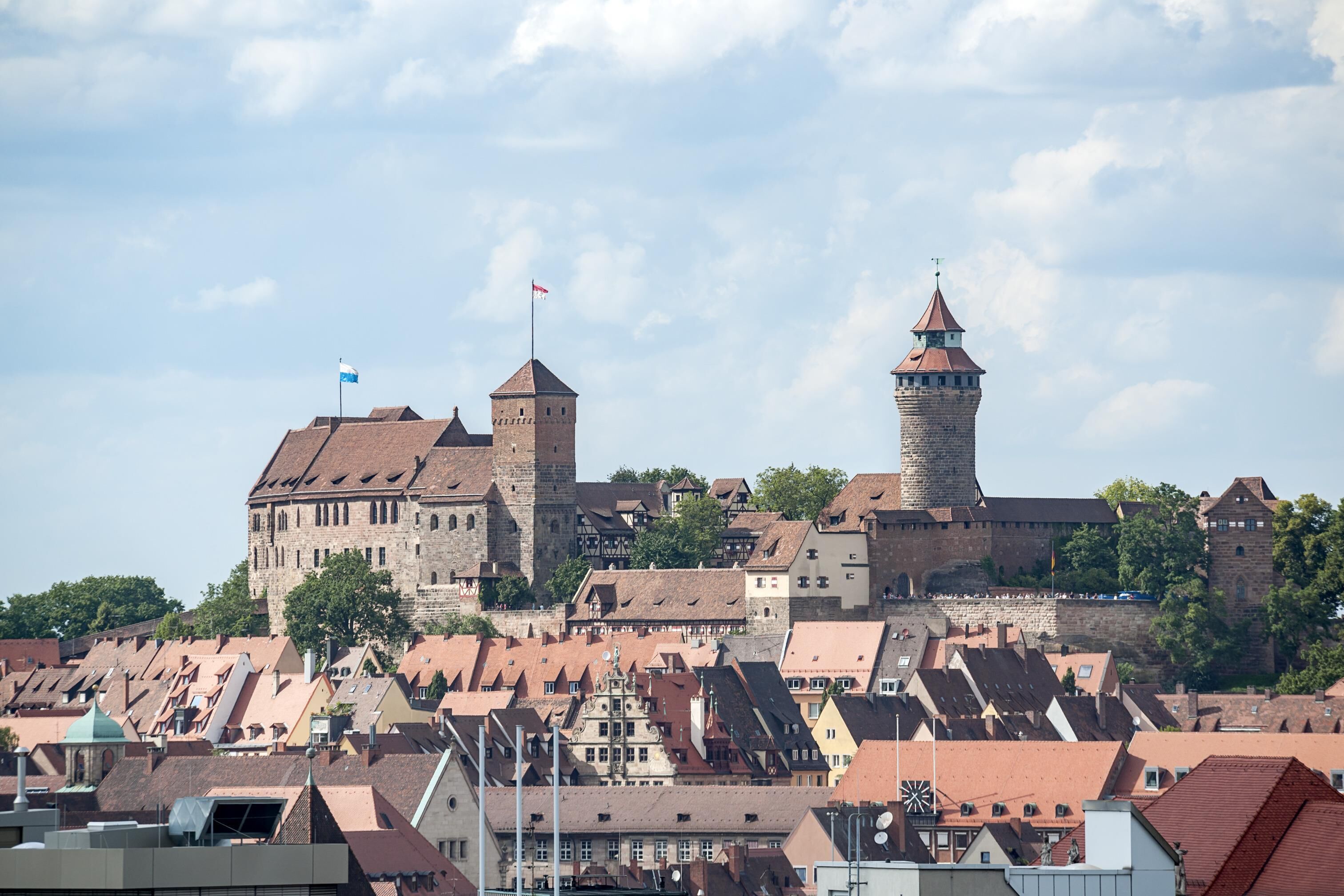 A historic castle with a prominent tower, surrounded by traditional buildings with steeply pitched roofs.