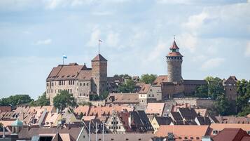 A historic castle with a prominent tower, surrounded by traditional buildings with steeply pitched roofs.