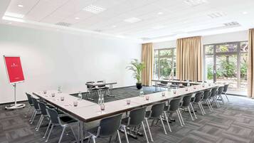 A conference room with a long table, chairs, a projector, and a potted plant.