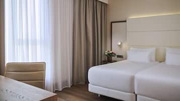 Habitación de hotel con cama, una silla, una mesa y ventana con cortinas.