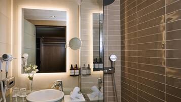Un baño moderno con cabina de ducha de vidrio, un lavamanos con espejo y artículos de tocador en la encimera.