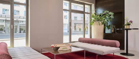 Una sala de estar moderna con un sofá, una mesa de centro y un ventanal con vistas a edificios.