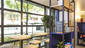 A modern library with large windows, comfortable seating, and a variety of books and plants.