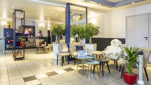 A modern hotel lobby with a check-in desk, seating area, and a large mirror.