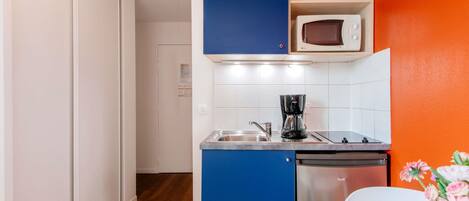 Una kitchenette funcional con microondas, cafetera y lavavajillas.