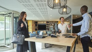 Een moderne hotellobby met een receptiebalie, een kassa en een computer.