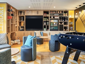 A modern living room with a flat-screen TV, seating area, and a game table.