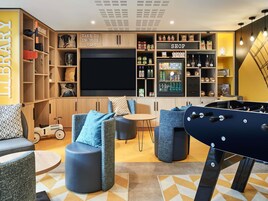 A modern living room with a flat-screen TV, seating area, and a game table.