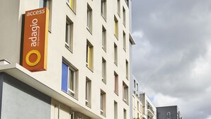 Un bâtiment moderne avec une enseigne indiquant « Adagio City, hôtel-appartements » et de nombreuses fenêtres.