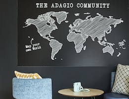 A wall with a world map and the text "THE ADAGIO COMMUNITY" and "Map your own World".