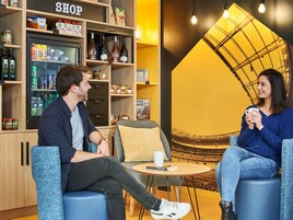 Un interior moderno con una tienda, un área de descanso y un cartel grande de un estadio.