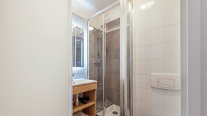 Une salle de bain moderne avec une douche à parois de verre, un lavabo avec un miroir et des toilettes.