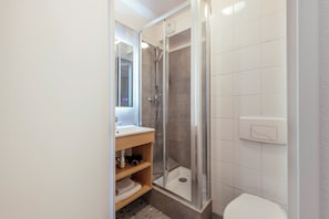 A modern bathroom with a glass-enclosed shower, a sink with a mirror, and a toilet. - Aparthotel Adagio Access Paris Saint-Denis Pleyel (Saint-Denis)