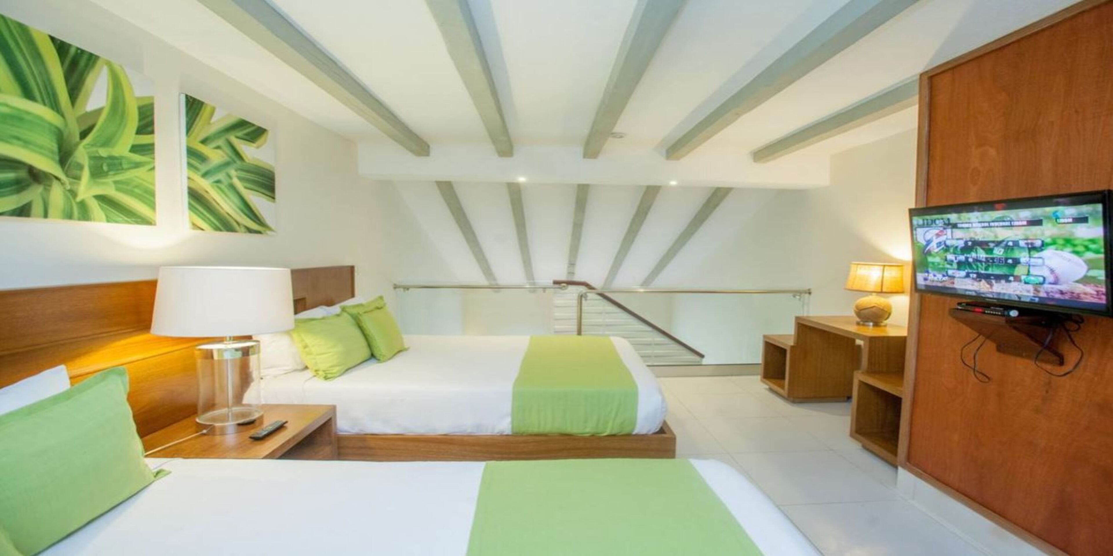 A hotel room with a bed, a TV, a desk, and a staircase.
