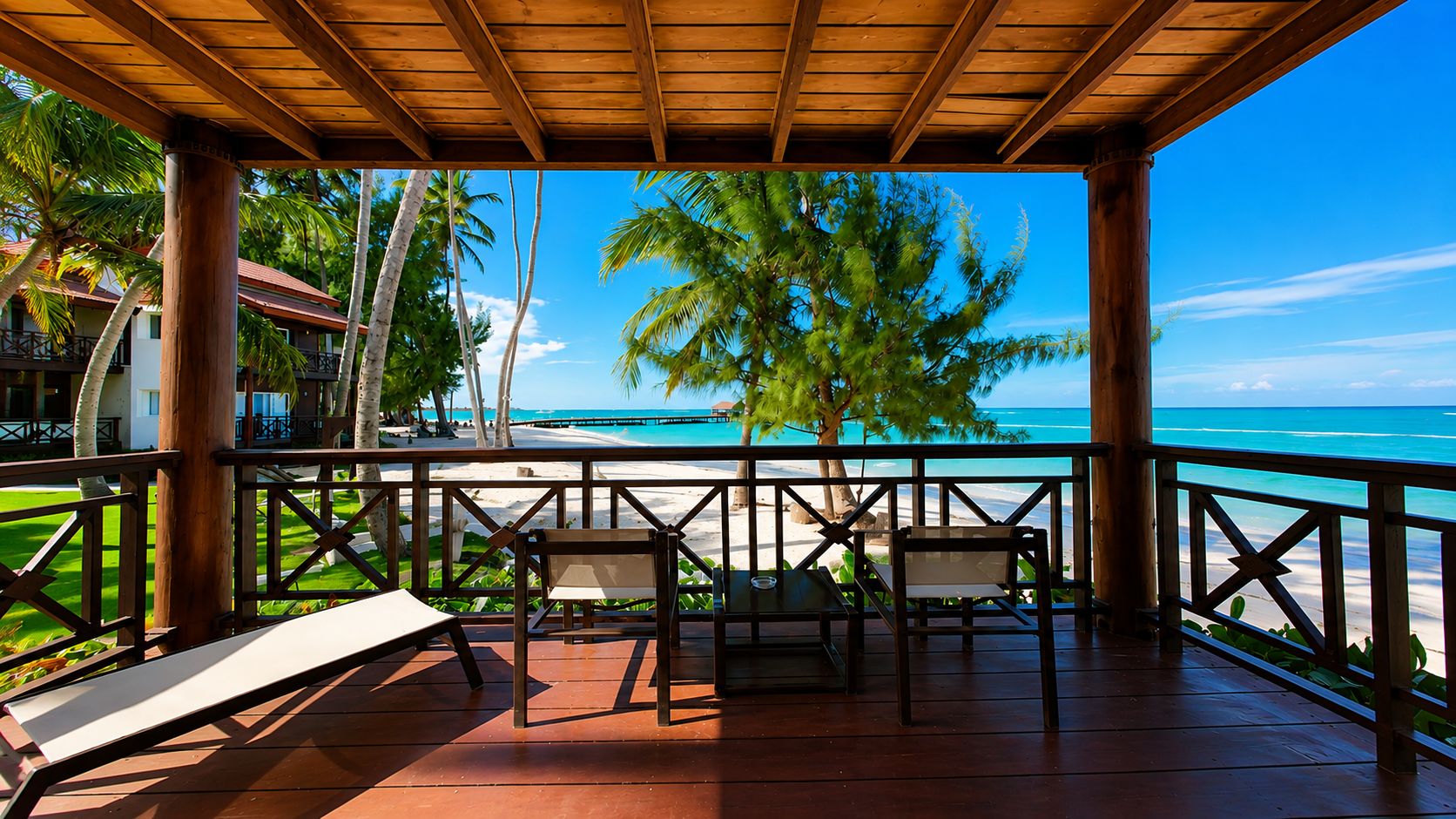 Una terraza de madera con vista a una playa y palmeras.