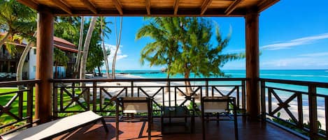 A wooden deck with a view of a beach and palm trees.