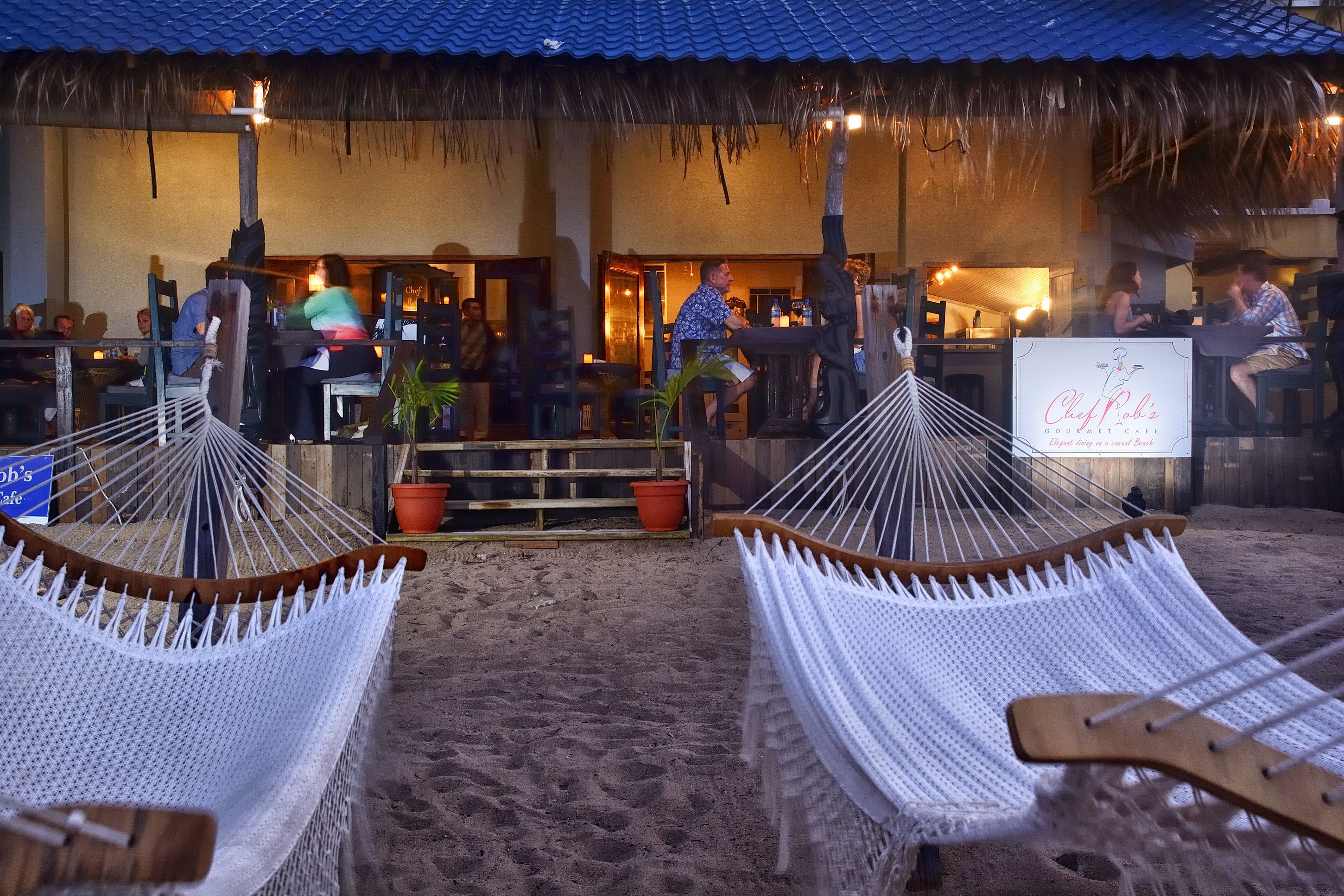 Un restaurante frente al mar con terraza, que incluye hamacas y un letrero que dice 'Chef Rob'.