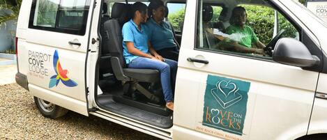 Una camioneta blanca con la leyenda "Parrot Cove Lodge" y "Hot Rock Grill Restaurant", que indica un servicio de alojamiento y restaurante.