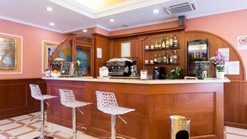 A bar area with a wooden counter, bar stools, and a coffee machine.