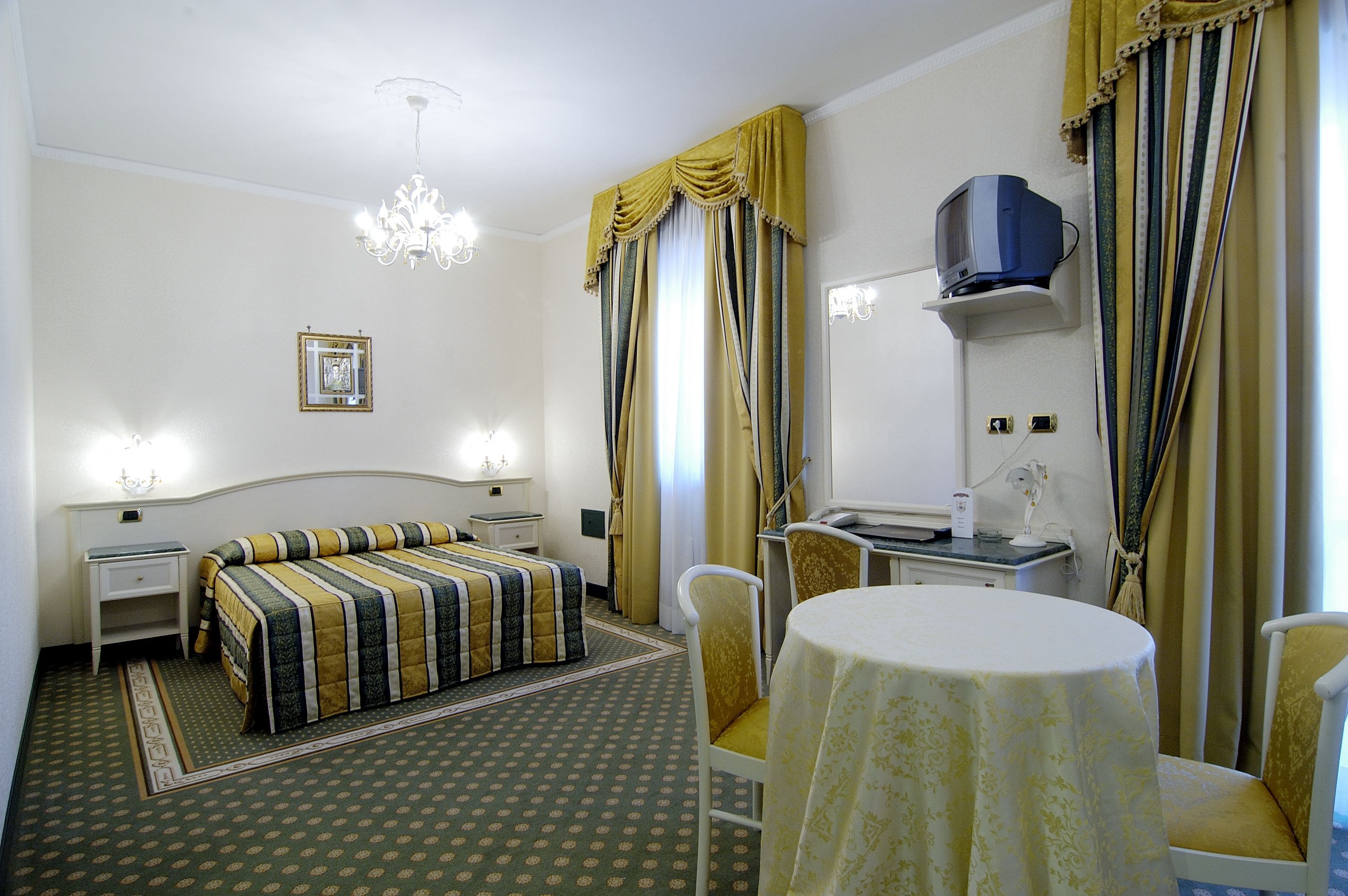 Ein Hotelzimmer mit Bett, Nachttisch, Lampe, Stuhl und einem Tisch mit Tischdecke.