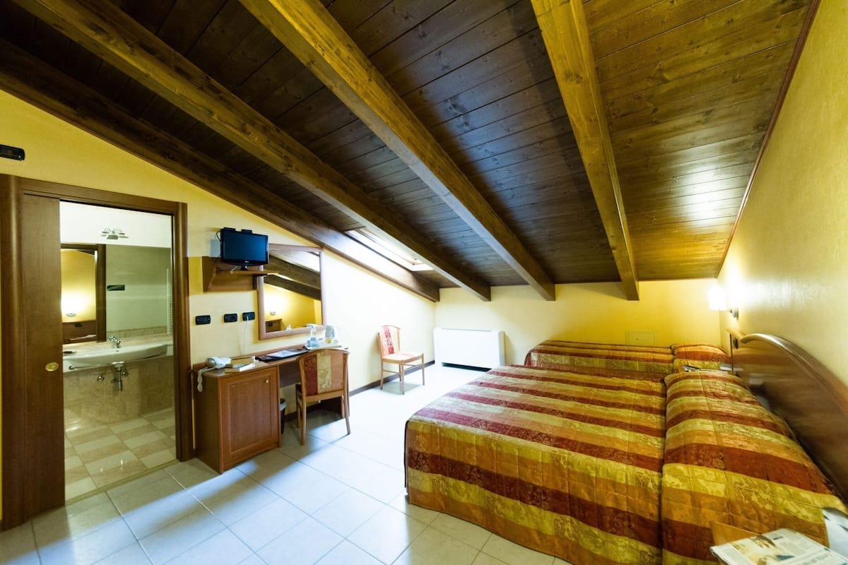 Ein Zimmer mit Bett, Schreibtisch, Stuhl, Spiegel und Fenster.