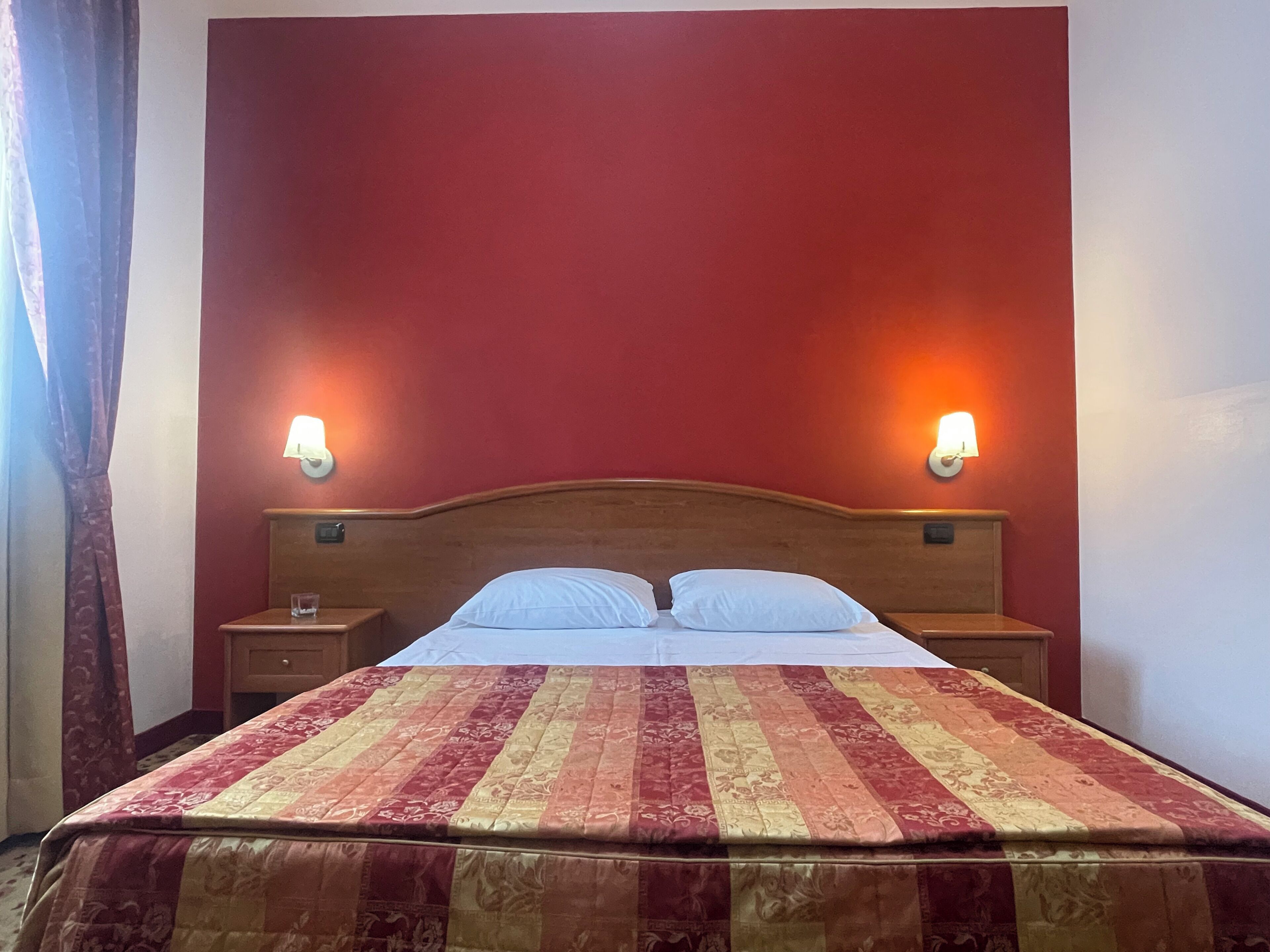 Een bed met een gestreept sprei, twee nachtkastjes en wandlampen.