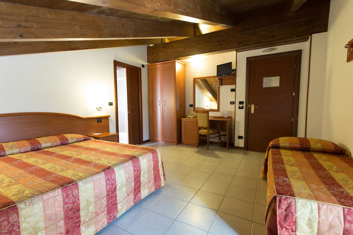 Ein Hotelzimmer mit zwei Betten, einem Schreibtisch, einem Stuhl und einem Spiegel.