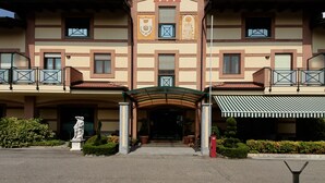 Un hotel con fachada simétrica, una entrada central con dosel y una estatua al frente.