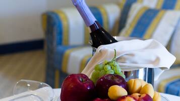A fruit bowl with grapes, apples, and a bottle of wine on a table.