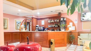 Una zona de bar con mostrador de madera, estantes llenos de botellas de licor y una máquina de café.