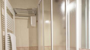 A bathroom with a shower enclosure, a towel rack, and a sink.