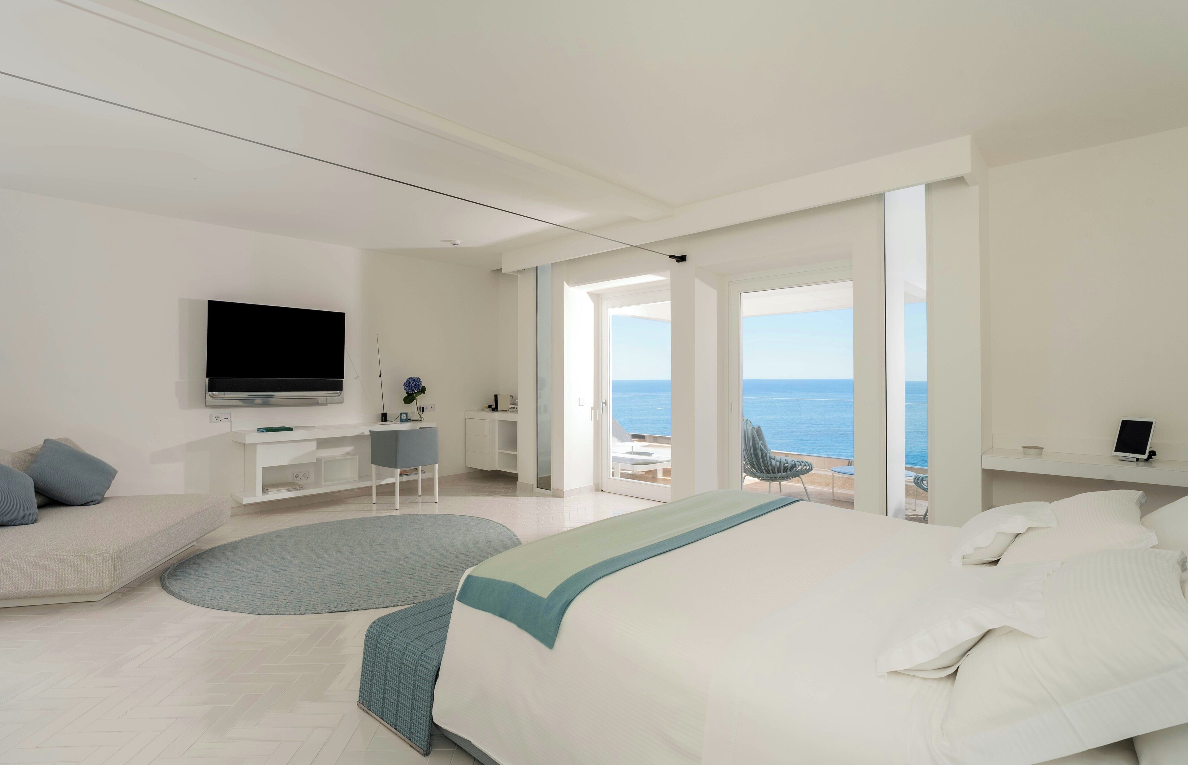 Una habitación de hotel moderna con una cama grande, televisión, escritorio y vista al mar.