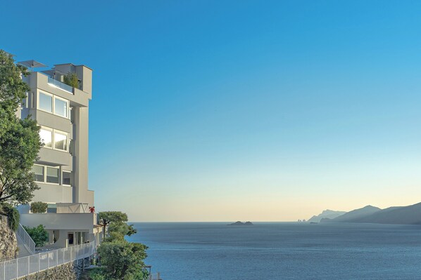 A modern building with balconies overlooking a calm sea and distant mountains. - Casa Angelina (Praiano)