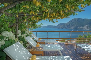 A wooden deck with lounge chairs and a pergola with lemons. - Casa Angelina (Praiano)
