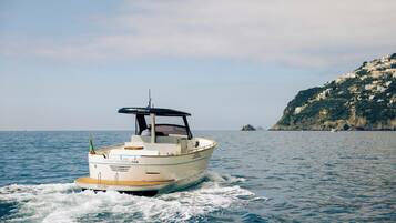 A boat named 'Lady Angelina' on a body of water with a coastal landscape in the background.