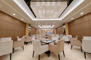 Ein geräumiger Hotel-Speisesaal mit mehreren Tischen und Stühlen, einer großen Chandelier und einem modernen Interieur.