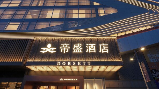 Un hôtel moderne, reconnaissable à son grand panneau « Dorsett », à ses larges fenêtres et à son entrée bien éclairée.