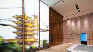 Un intérieur moderne avec de grandes fenêtres, un comptoir d’accueil et un mur orné d’œuvres d’art reflétant la culture locale.