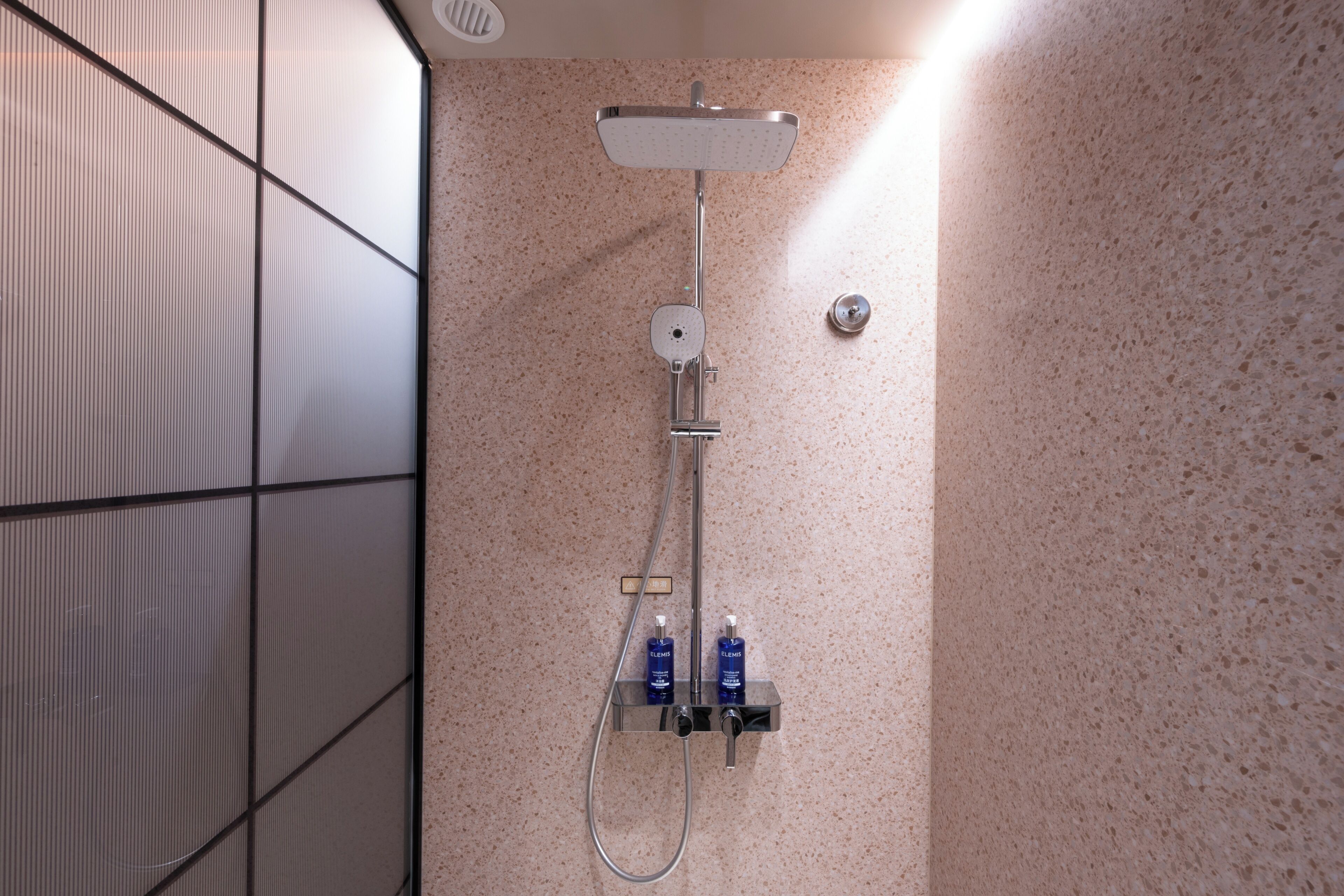 Una ducha moderna con cabezal de ducha de mano y panel de control en la pared.