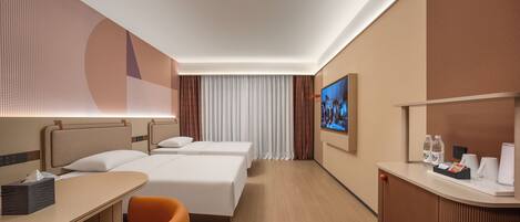 A hotel room with two beds, a desk, a chair, a TV, and a reception desk with amenities.