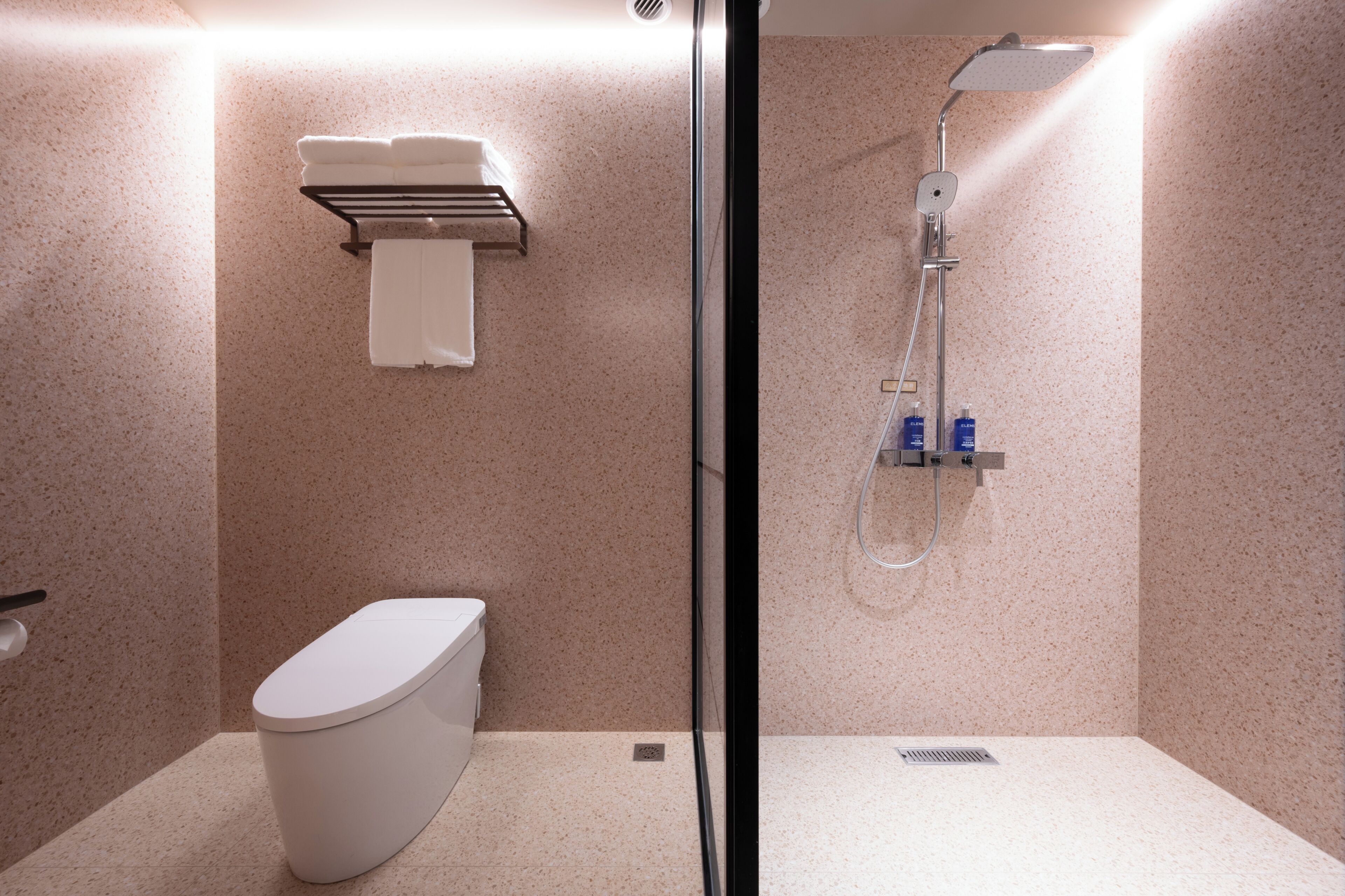 A modern bathroom with a toilet, a glass-enclosed shower, and a towel rack.