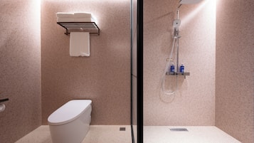 A modern bathroom with a toilet, a glass-enclosed shower, and a towel rack.