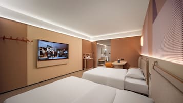 A hotel room with two beds, a TV, a small desk, and a bathroom visible through a door.