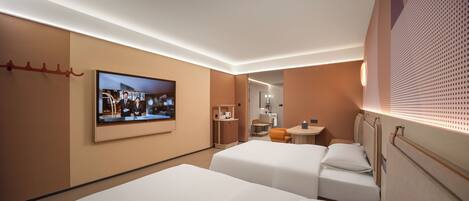 Habitación de hotel con dos camas, televisión, escritorio pequeño y baño visible a través de una puerta.