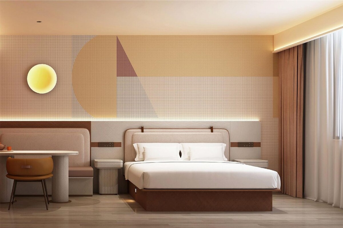 Una habitación de hotel moderna con una cama, mesitas de noche, un escritorio y una silla.