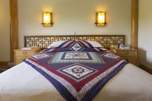 Een bed met een quilt met patroon, twee nachtkastjes met lampen, en een houten hoofdbord.