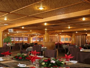 Un ristorante con diversi tavoli apparecchiati per la cena, caratterizzato da un soffitto in legno caldo e un'atmosfera accogliente.