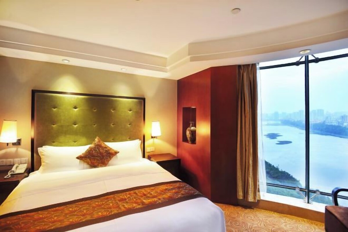 Une chambre d’hôtel avec un grand lit, une vue sur une rivière et un panorama sur la ville.
