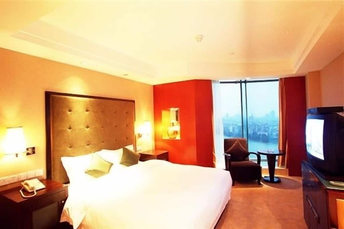 Een hotelkamer met een groot bed, een televisie, een bureau en een stoel.