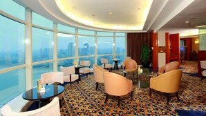 A hotel lobby with large windows, a patterned carpet, and seating arrangements.